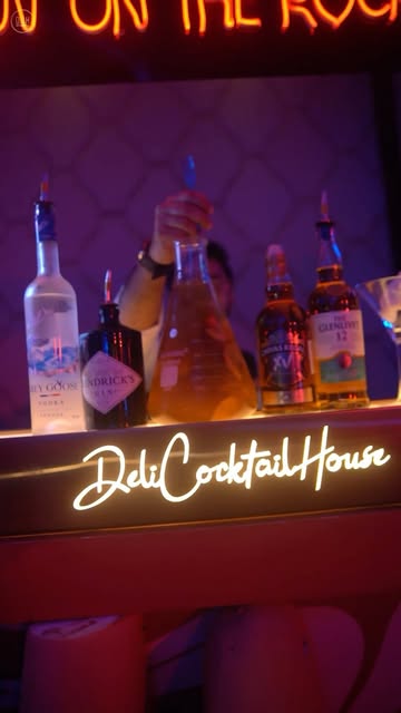 Neon Deli Cocktail House bar sign with premium bottles